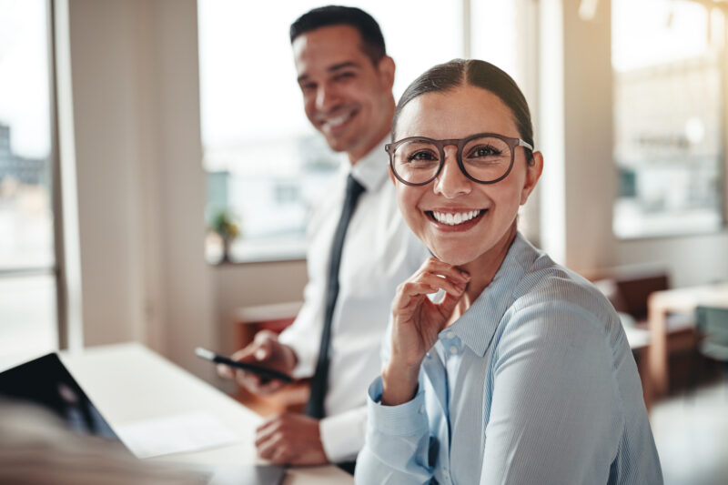 Smiling young businesswoman having a meeting with a coworker around a table during a meeting in a modern office