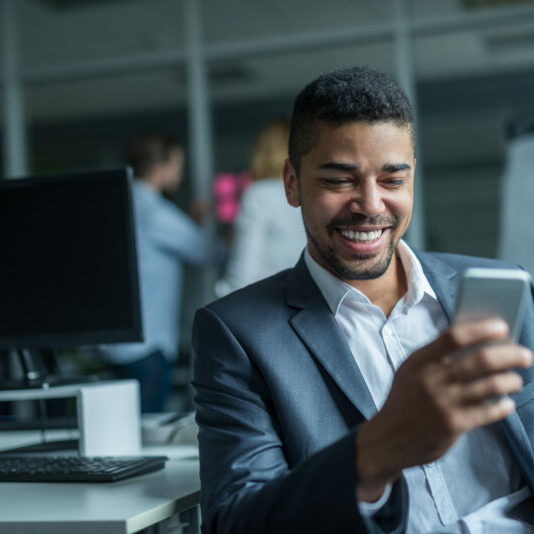 Happy african american businessman using a mobile phone in an office.