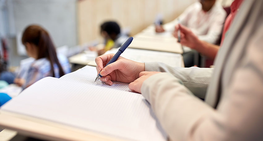 A law student sits in a classroom with other students while taking a law school final exam