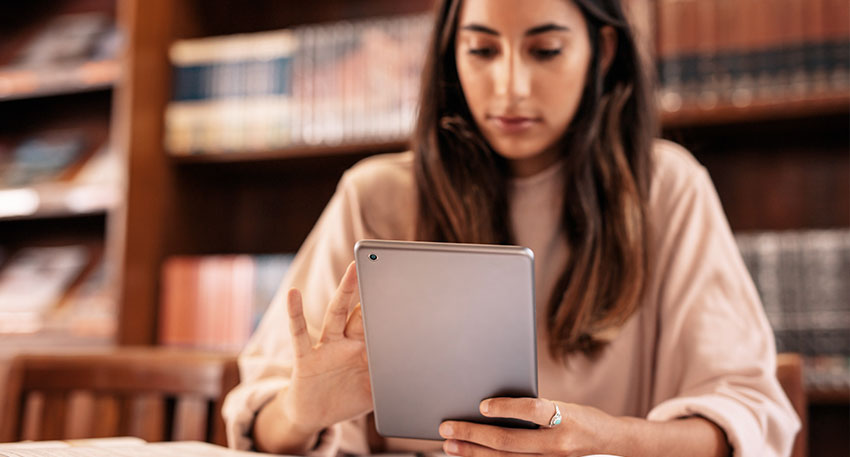 A female law student researches law school final exam tips at the law library